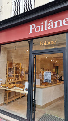Entrée de la boulangerie Poilâne rue de Lévis, vitrine de pains au levain et viennoiseries