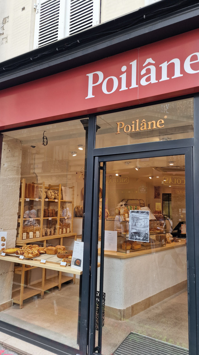 Entrée de la boulangerie Poilâne rue de Lévis, vitrine de pains au levain et viennoiseries