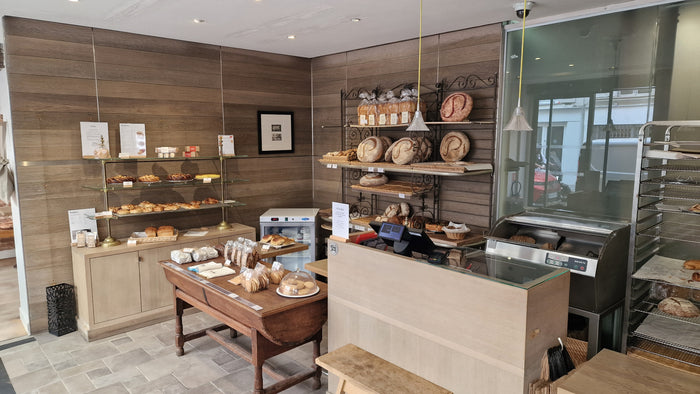 Intérieur de la boulangerie Poilâne du Marais avec miches au levain, viennoiseries et comptoir en bois