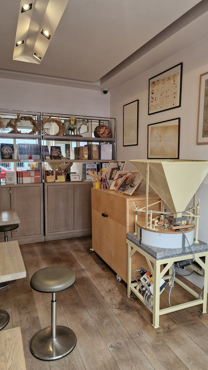 Moulin à meule de pierre et coin librairie dans la boutique Poilâne du Marais
