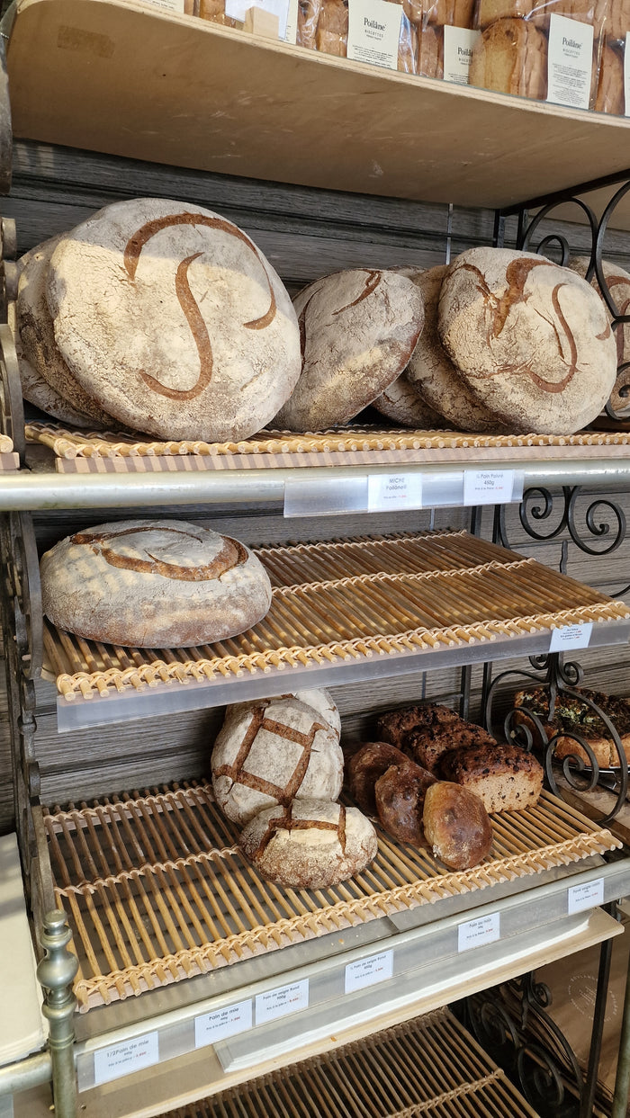 Miches Poilâne et pains au levain sur les étagères de la boulangerie du Marais